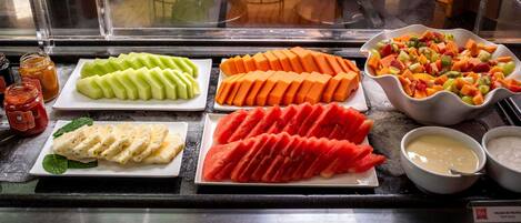 Presentación de una ensalada de frutas con diferentes frutas y salsas.