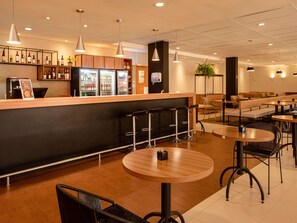 A modern bar area with a counter, stools, and seating. - ibis Betim (Betim)