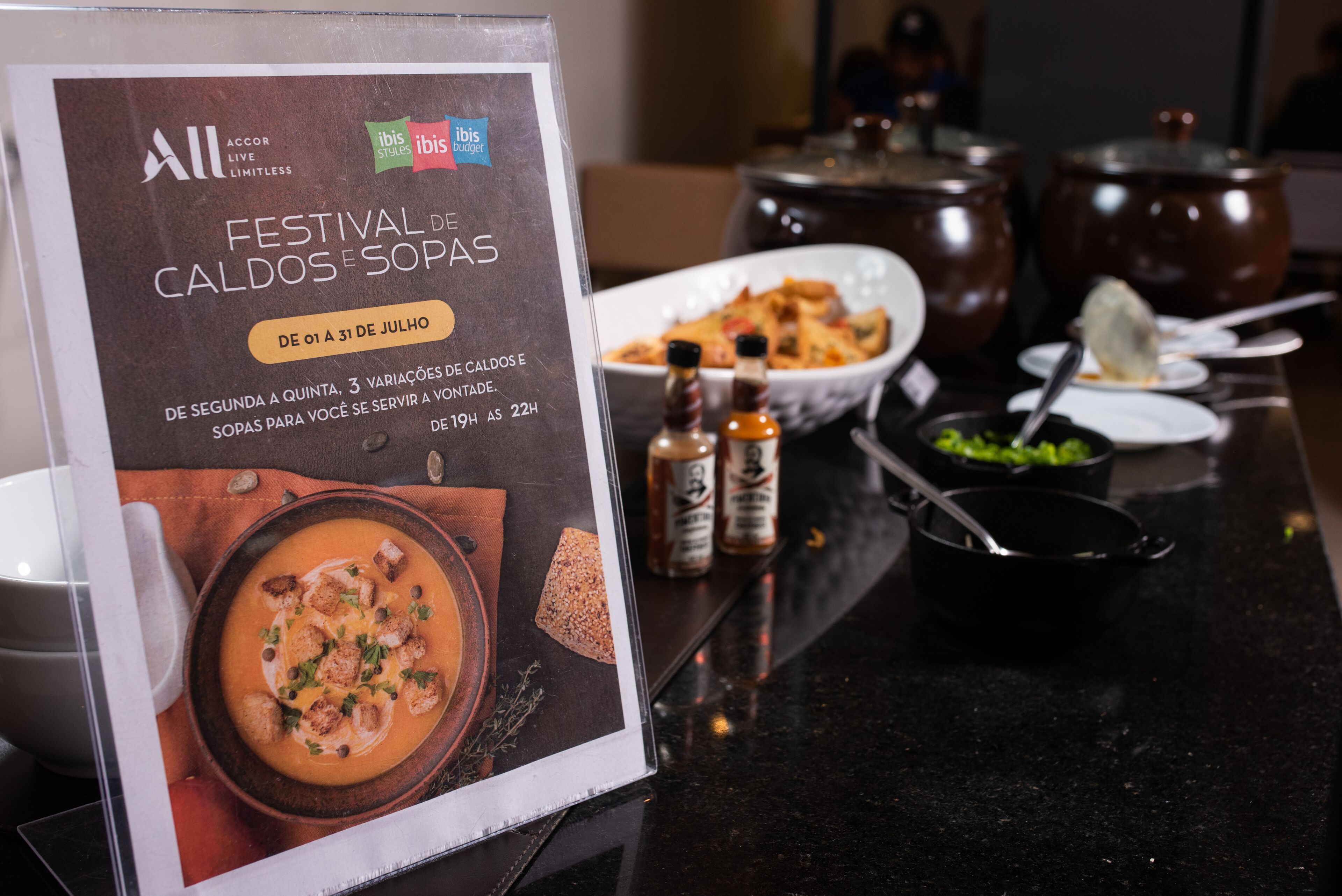 Un menú de restaurant amb un anunci de sopa, un bol de sopa i diferents condiments sobre la taula.