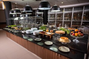 A buffet with various food items and a cake on a counter. - ibis Betim (Betim)