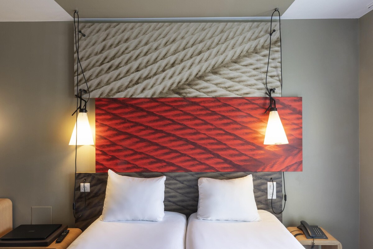 Een hotelkamer met een bed, nachtkastjes, een bureau, een lamp en een telefoon.