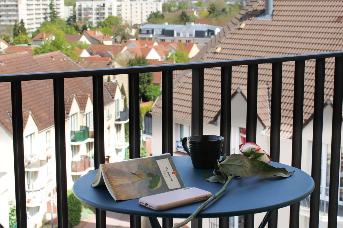 Een balkon met uitzicht op woongebouwen, een boek, een smartphone en een roos.