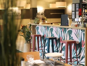 Un espace bar avec des tabourets, un comptoir et un mur décoratif.