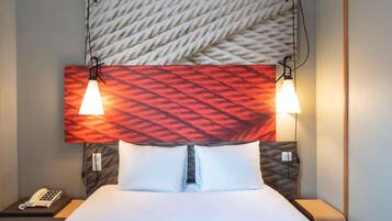 Quarto de hotel com uma cama, duas luminárias de apoio, um telefone e uma parede com textura.