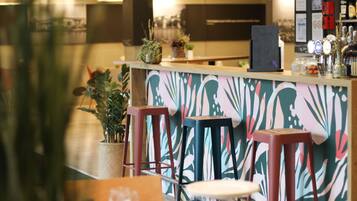 Een bar met krukken, een toonbank en een decoratieve wand.