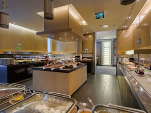 A buffet area with various food options, a Novotel sign, and a clear exit sign. - Novotel Muenchen Messe (Munich)