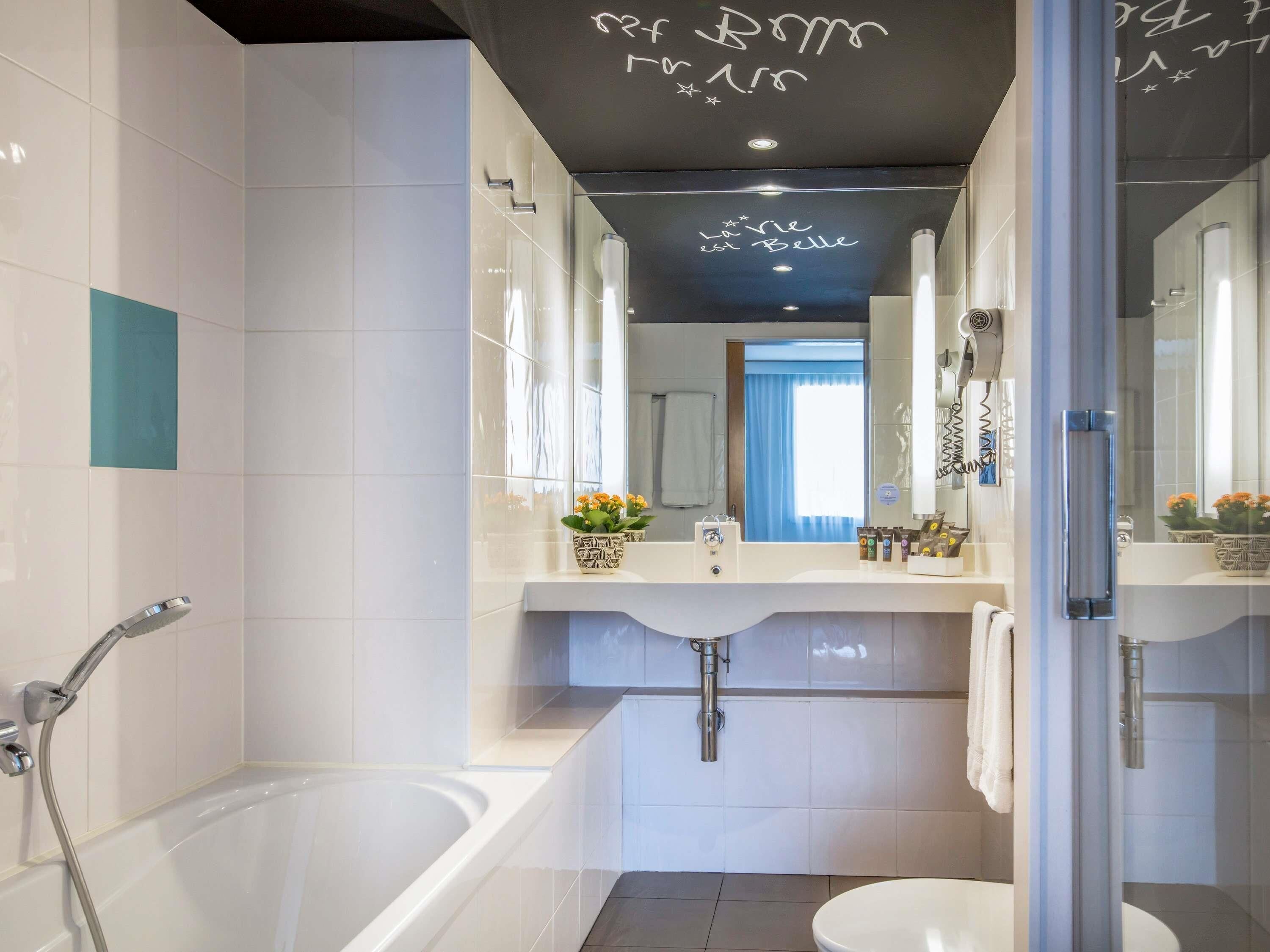 A modern bathroom with a bathtub, toilet, and a large mirror.