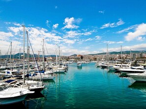 Marina con numerosas embarcaciones amarradas, agua tranquila y un paisaje urbano al fondo.