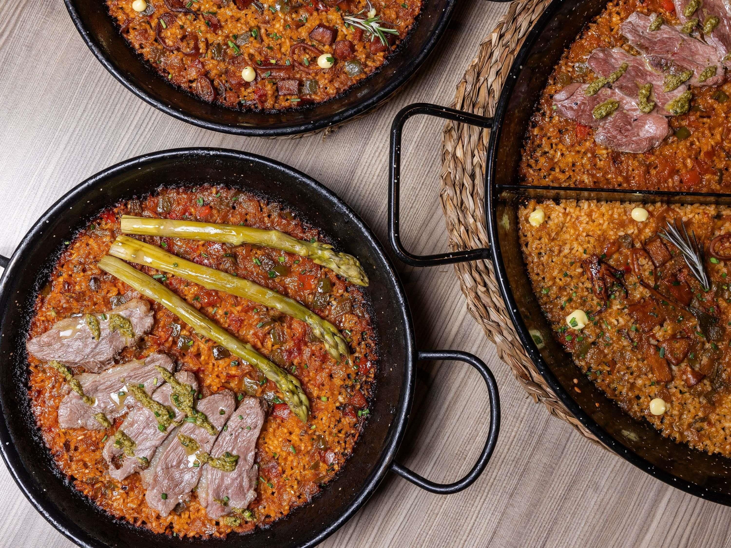 A large, black, cast-iron skillet filled with a dish that includes rice, meat, and asparagus.