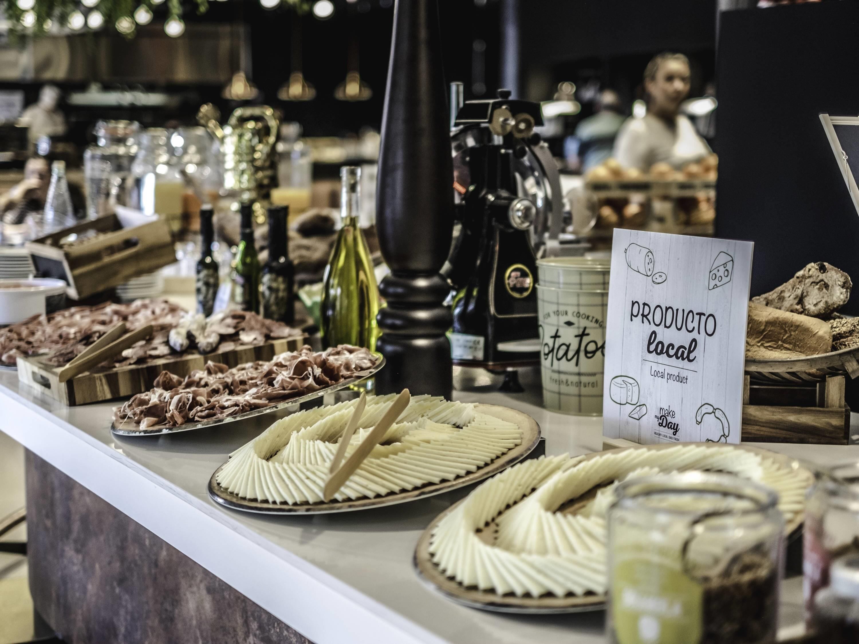 Un bufé con diferentes opciones de comida y un letrero que indica productos locales.