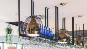 Un bar moderno con barra, cristalería y asientos.