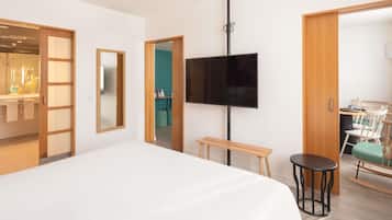 Una habitación de hotel moderna con una cama grande, un televisor de pantalla plana montado en la pared, un banco de madera y un pequeño taburete.