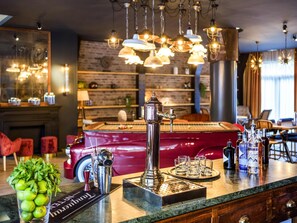 A bar area with a vintage car, a coffee machine, and a variety of bottles. - Novotel Barcelona Cornella (Cornella de Llobregat)