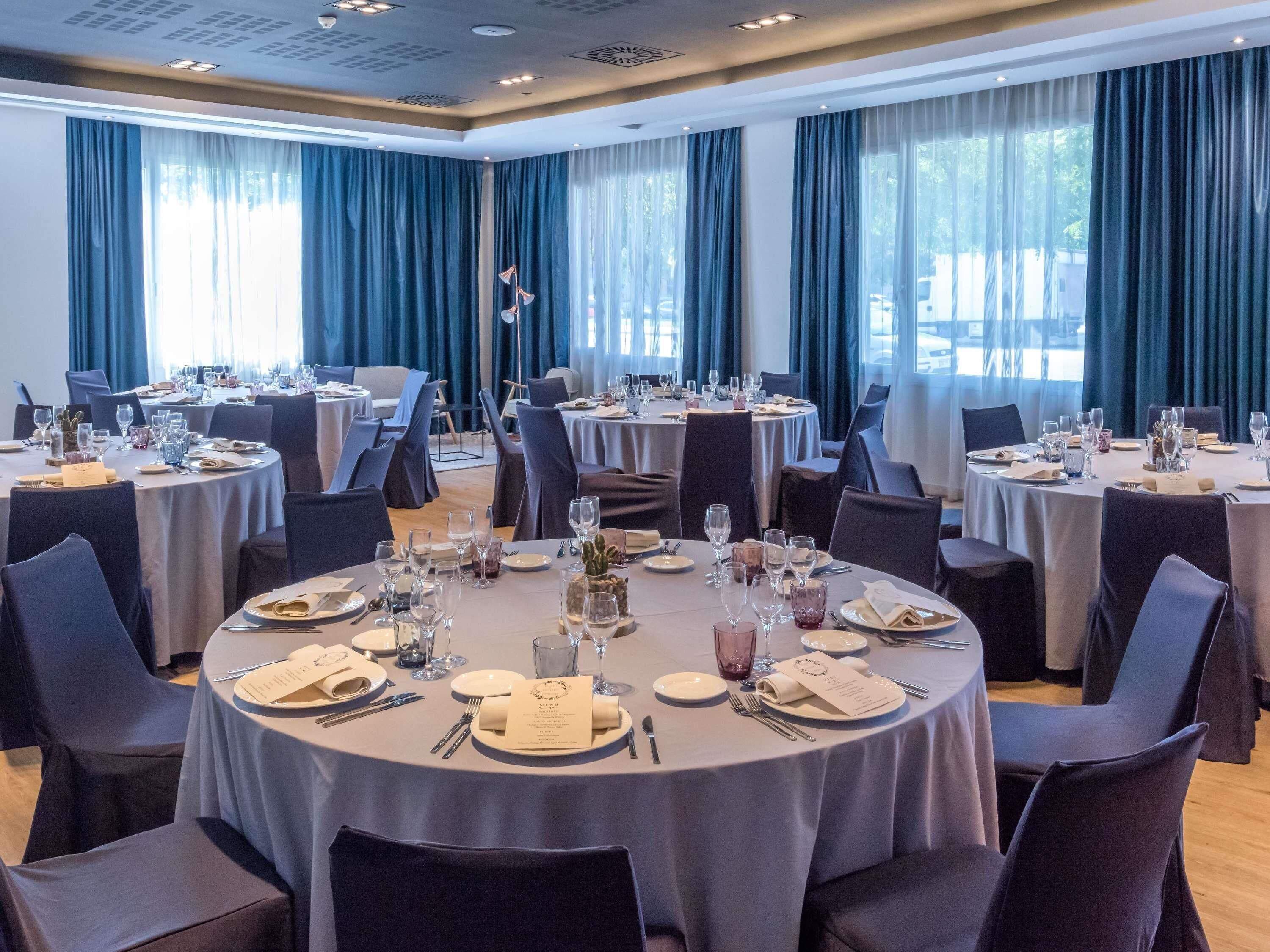 A large dining hall with round tables, chairs, and dining tables set for a meal.