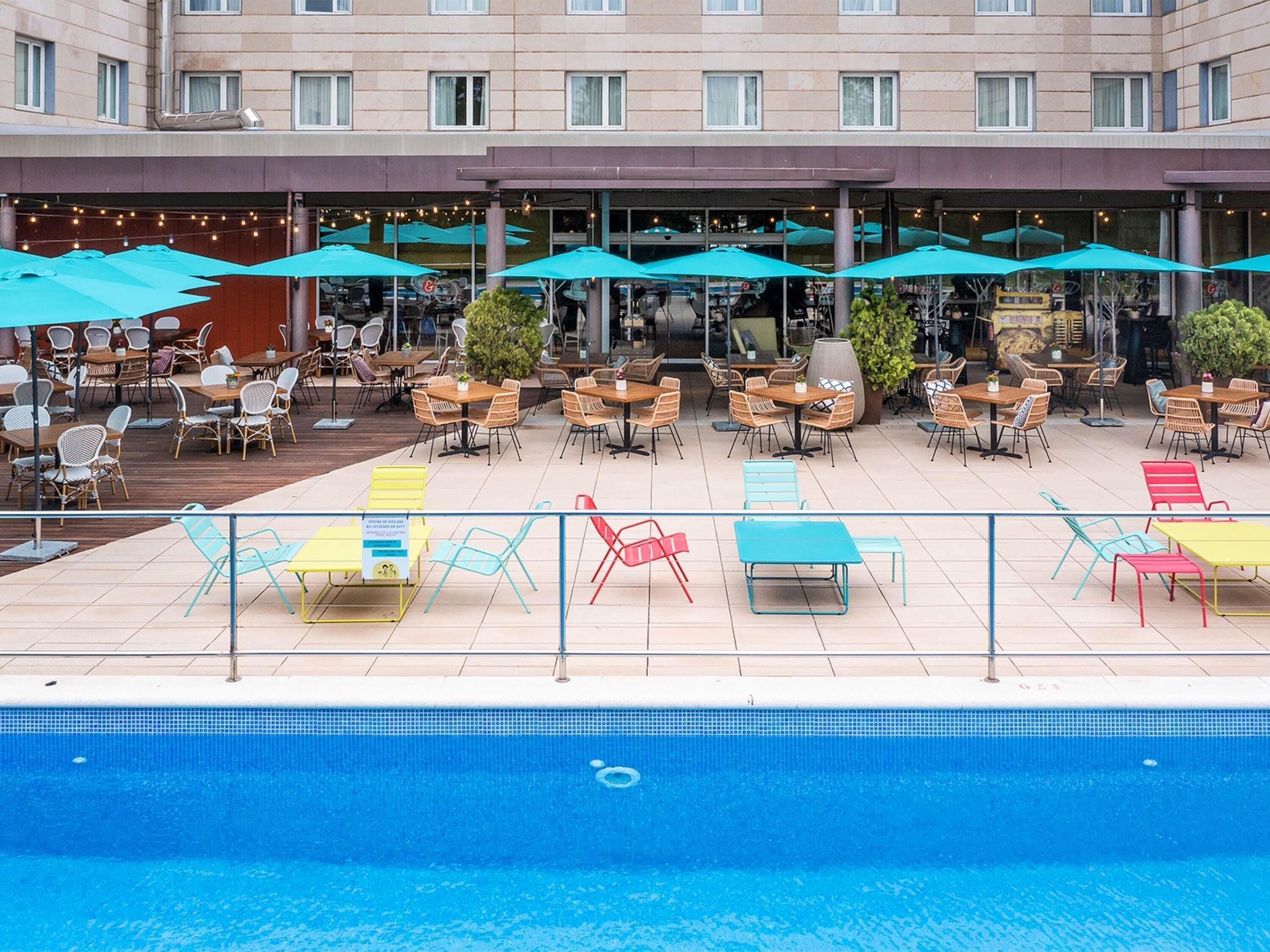 A hotel pool area with outdoor seating and umbrellas.