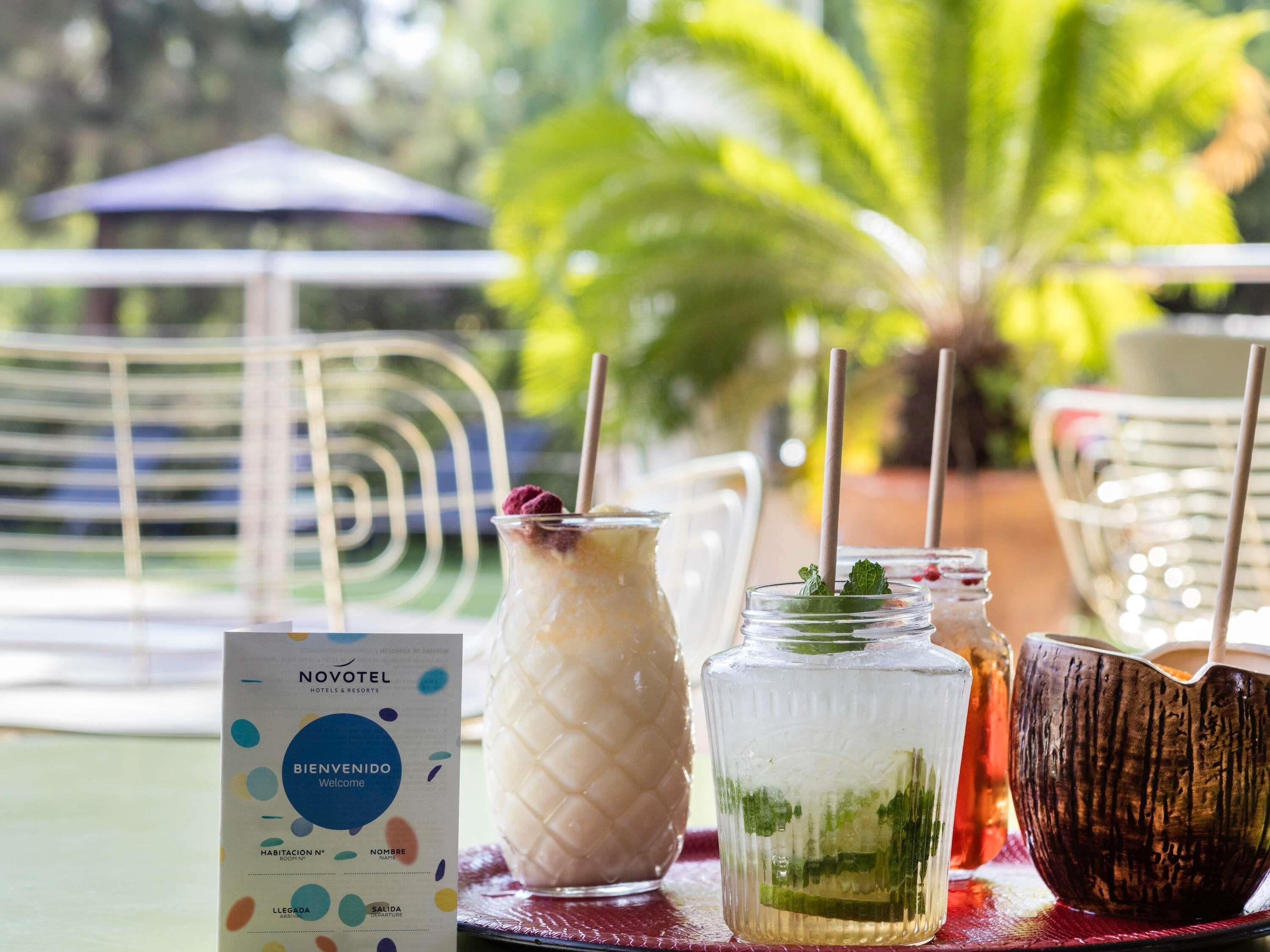 A table with a menu, a glass with a straw, and a drink with mint leaves.