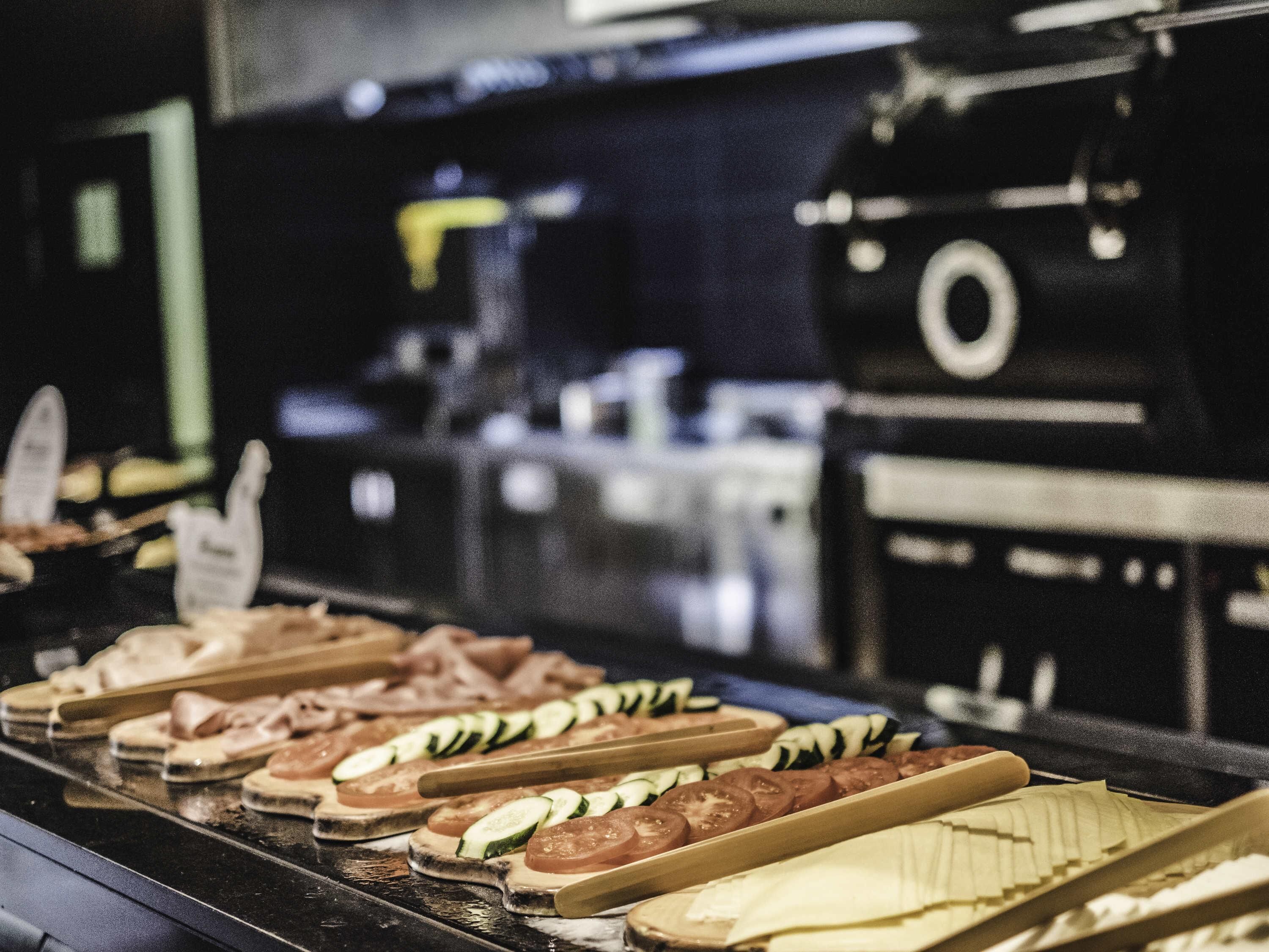Una encimera de cocina con diversos alimentos, como sándwiches y verduras en rodajas.