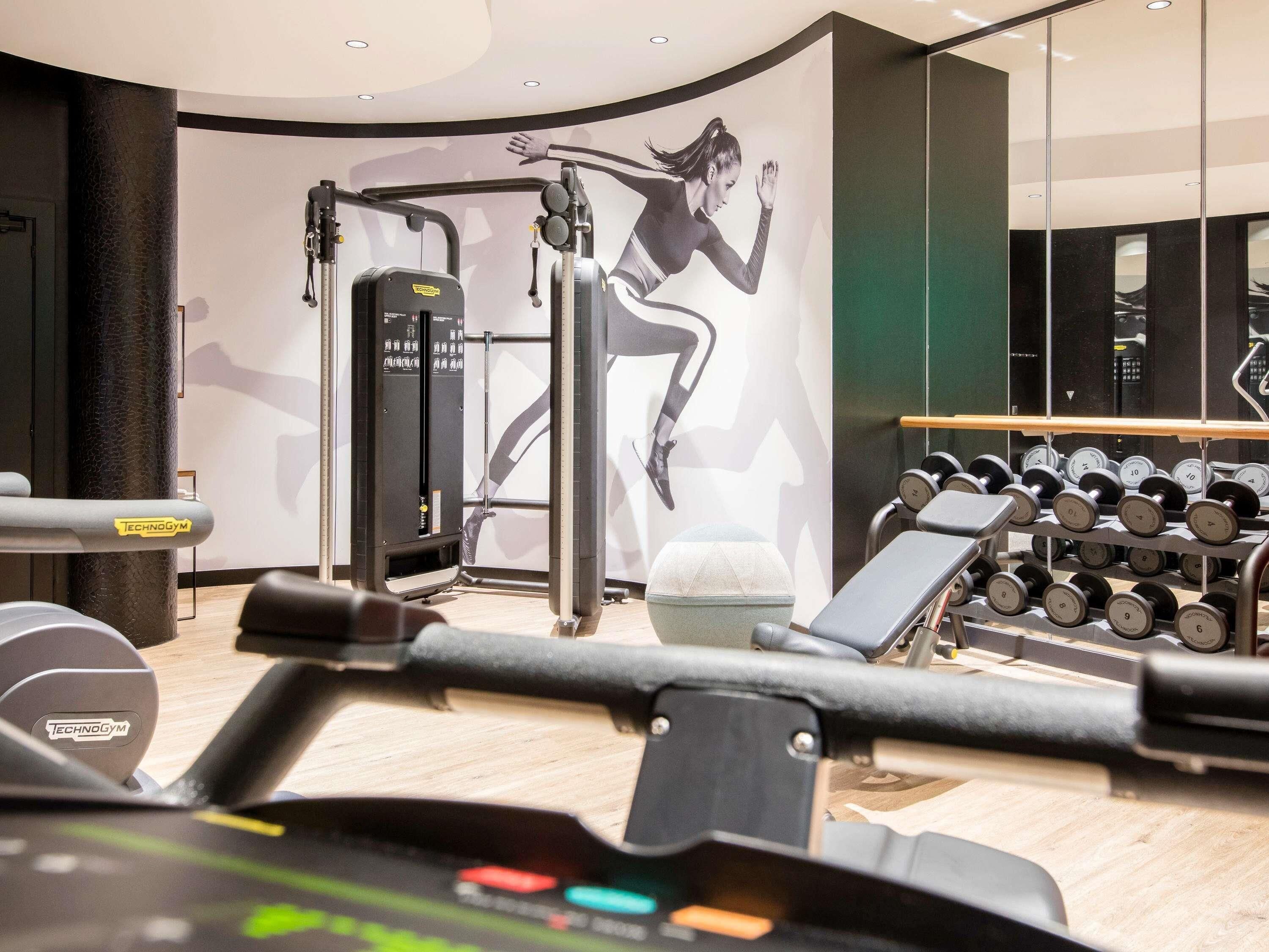 A gym with exercise equipment, a wall with a silhouette, and a mirror.