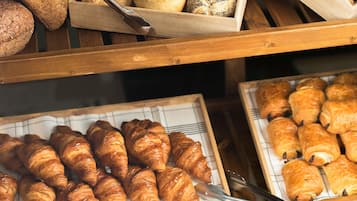 Eine Bäckertheke mit verschiedenen Brotsorten und Gebäck, darunter Croissants und Brötchen.