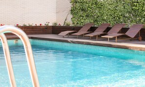 Una piscina al aire libre de temporada, sillones reclinables de piscina