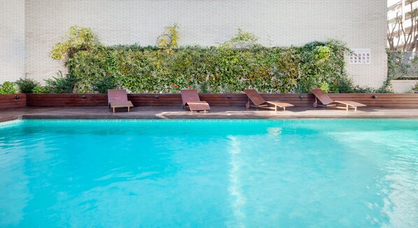 Una piscina al aire libre de temporada, sillones reclinables de piscina
