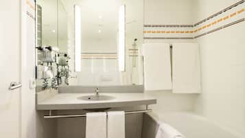 Un baño moderno con lavamanos, espejo y ducha.