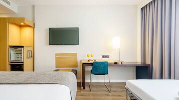 Habitación de hotel con dos camas, un escritorio, una silla, un televisor, una lámpara y un minibar.