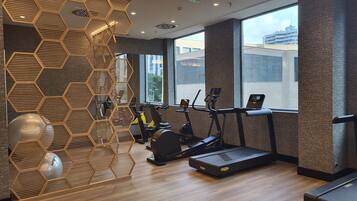 A modern gym with hexagonal wooden panels, treadmills, and exercise bikes.