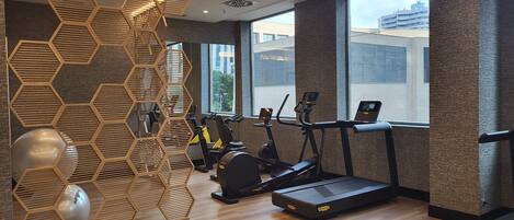 Un gimnasio moderno con paneles de madera hexagonales, cintas de correr y bicicletas estáticas.