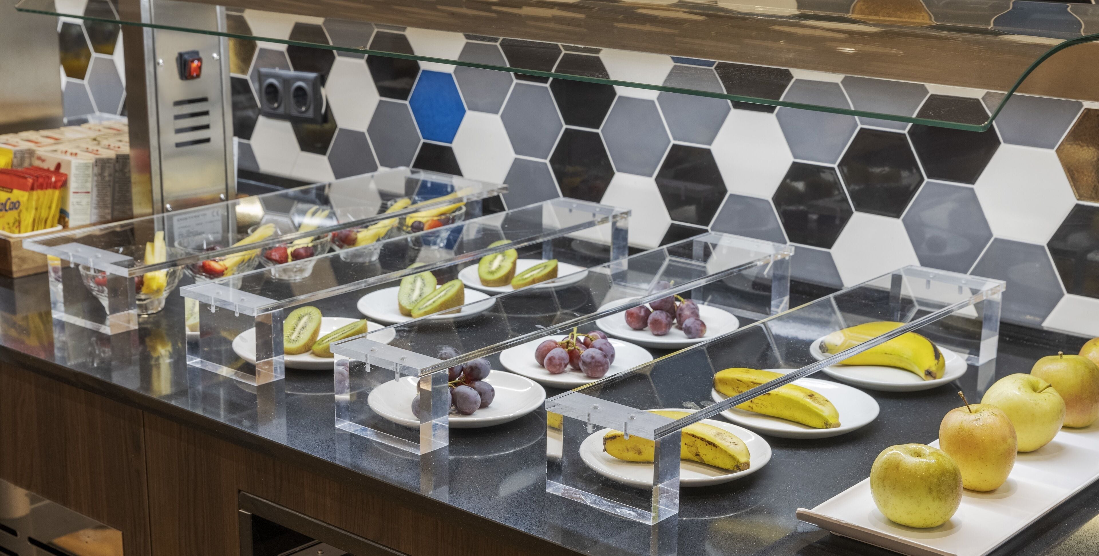 Un bufé de desayuno con diversas frutas y un salpicadero con diseño de panal.