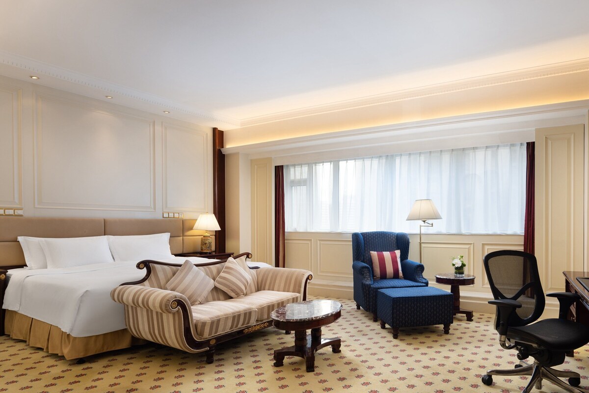 Une chambre d’hôtel comprenant un lit, un canapé, une chaise, une petite table et un bureau.