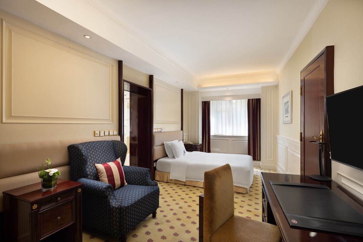 Une chambre d’hôtel avec un lit, un canapé, un bureau et une télévision.