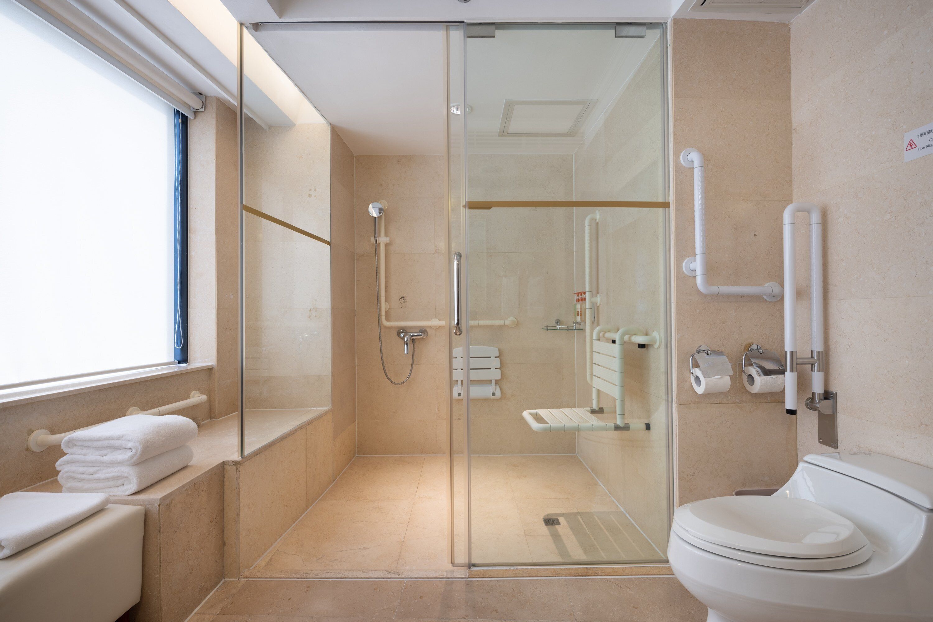 A modern bathroom with a glass-enclosed shower, a toilet, and a sink.