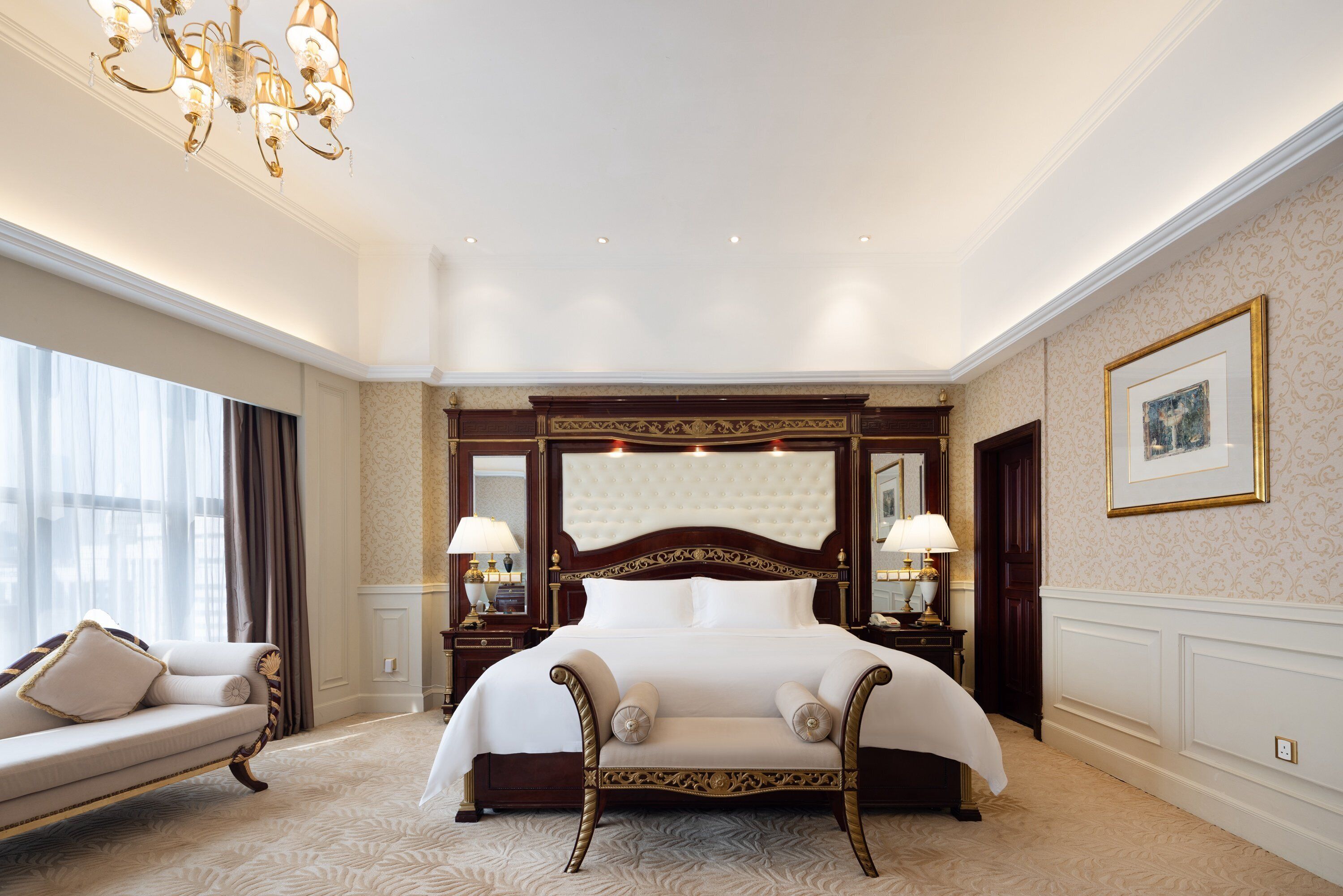Une chambre d’hôtel spacieuse, dotée d’un grand lit, d’un coin salon et d’un lustre.