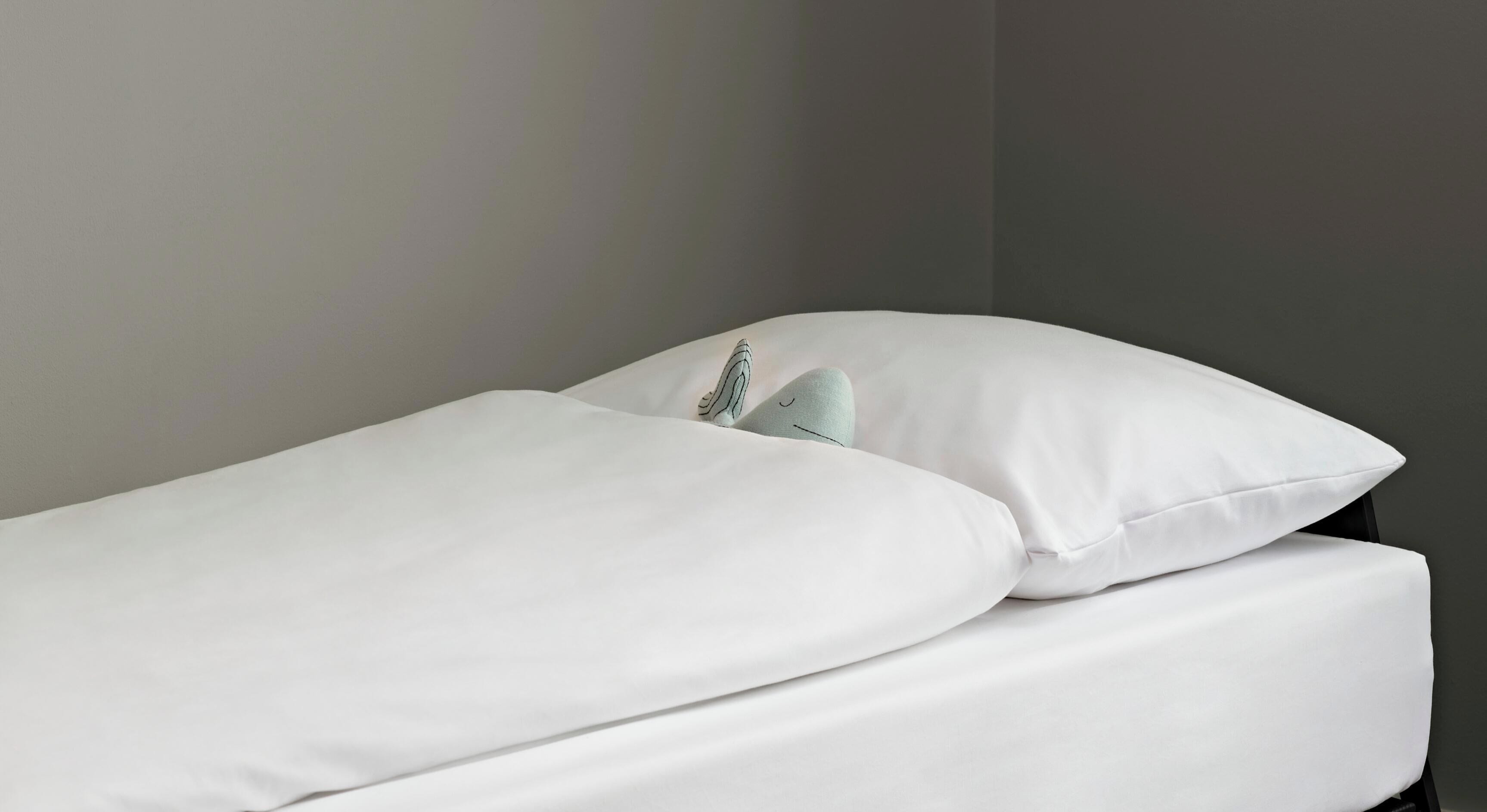 A bed with white bedding and a pillow.