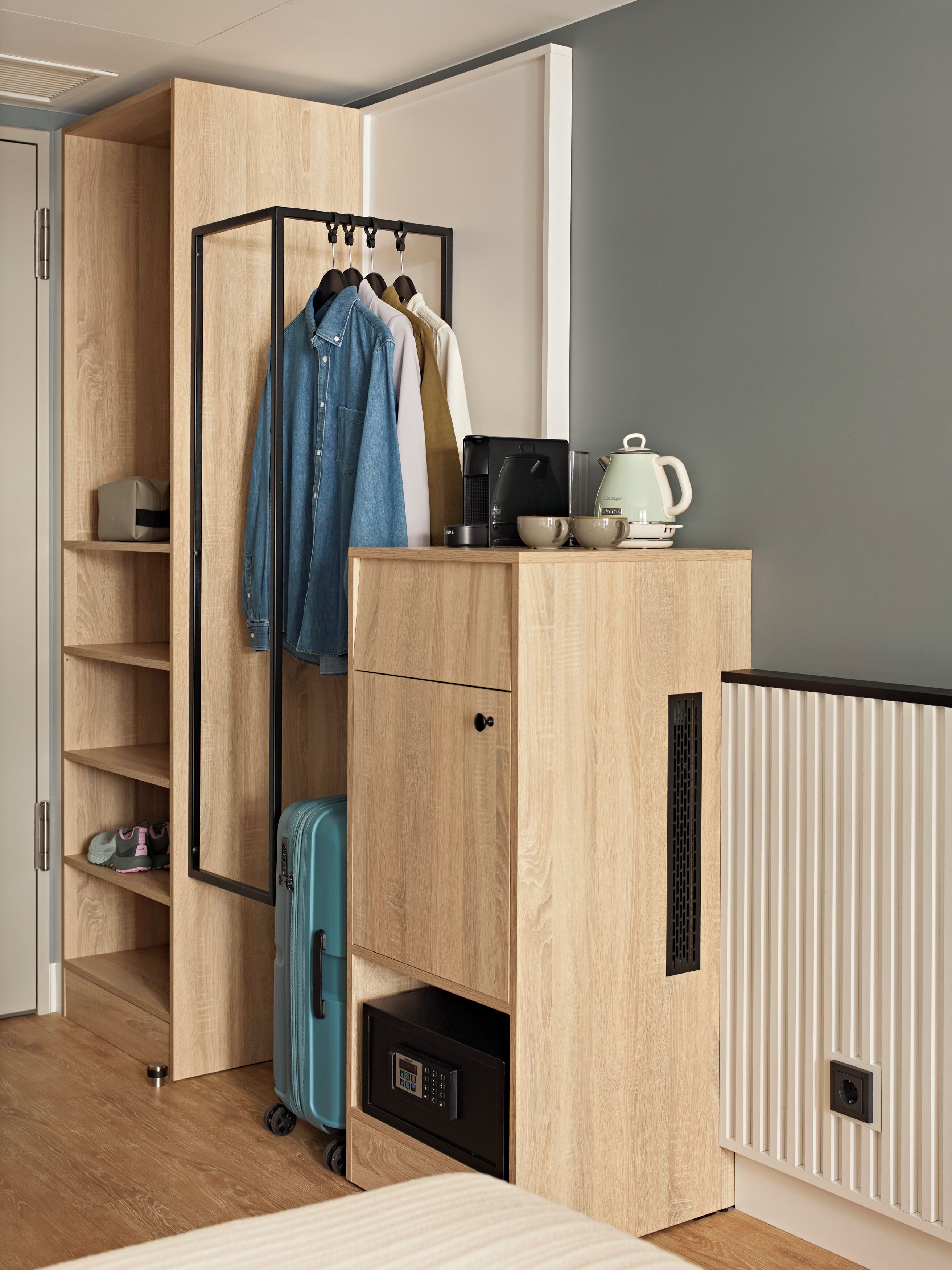 A compact room with a wardrobe, a small kitchenette, and a suitcase.