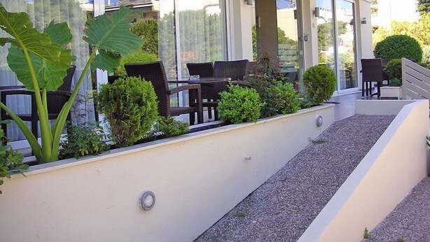 Un espace extérieur moderne aménagé avec une table et des chaises, entouré de jardinières et d’un petit escalier.