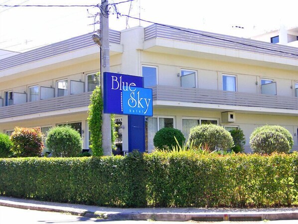A hotel named Blue Sky with a modern design, featuring a prominent blue sign, multiple windows, and well-maintained landscaping. - Blue Sky (Glyfada)