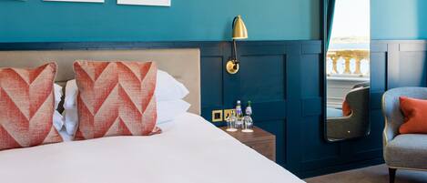 Ein Hotelzimmer mit Bett, Nachttisch, Spiegel und Stuhl.