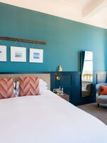 A hotel room with a bed, a nightstand, a mirror, and a chair.