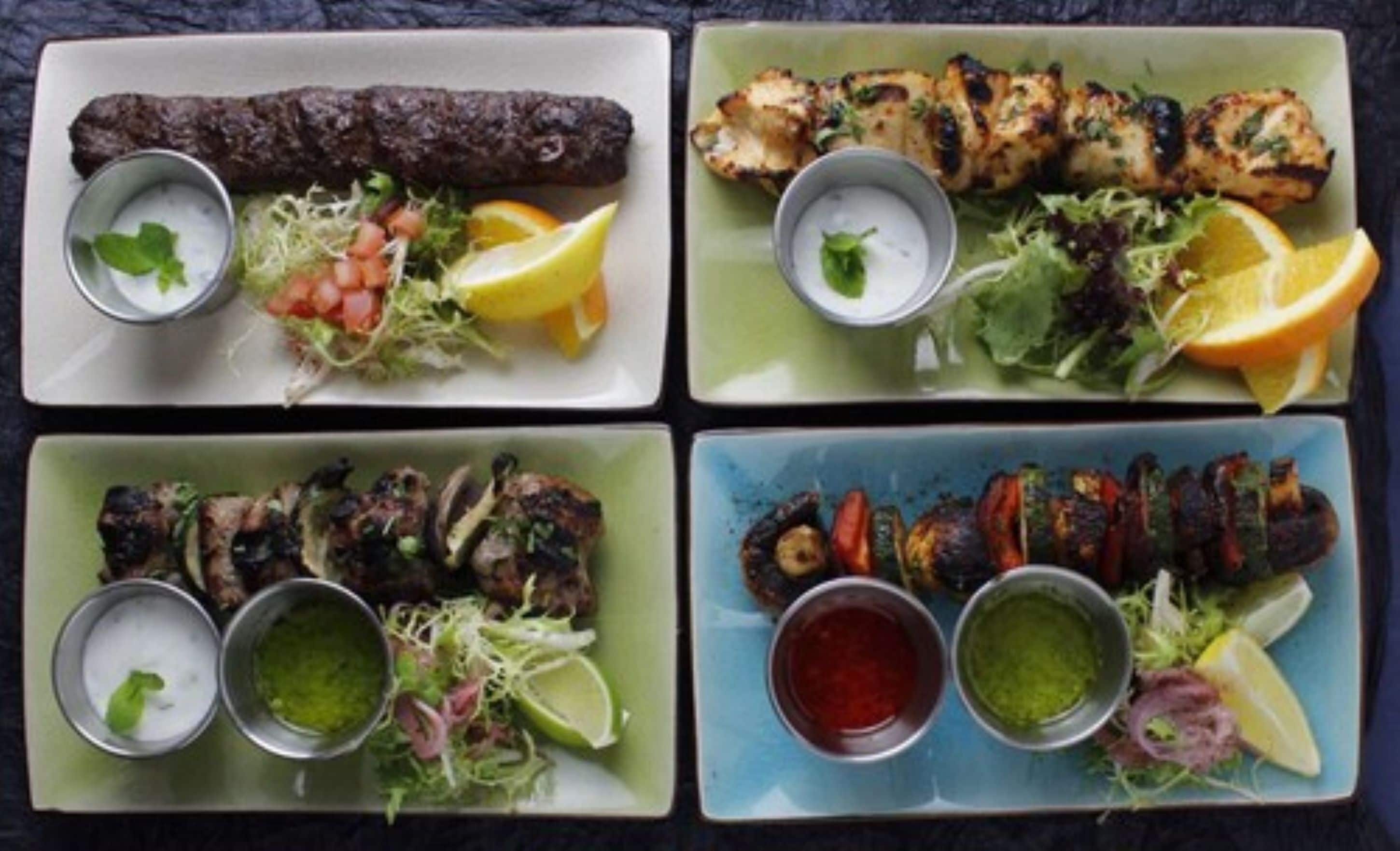 Cuatro platos con comida, varios guisos y acompañamientos.