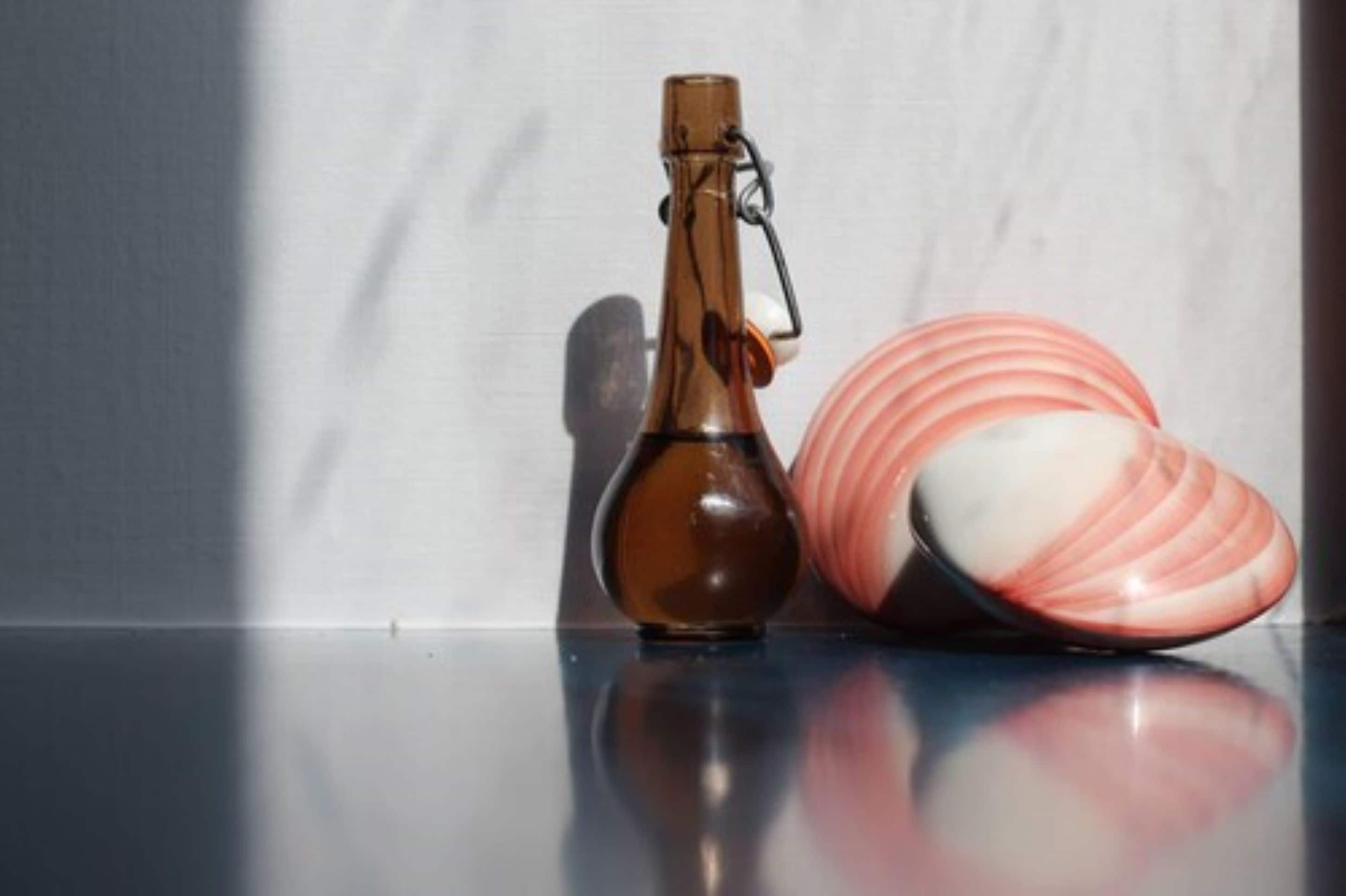 Una botella y un plato de cerámica sobre una superficie reflectante.