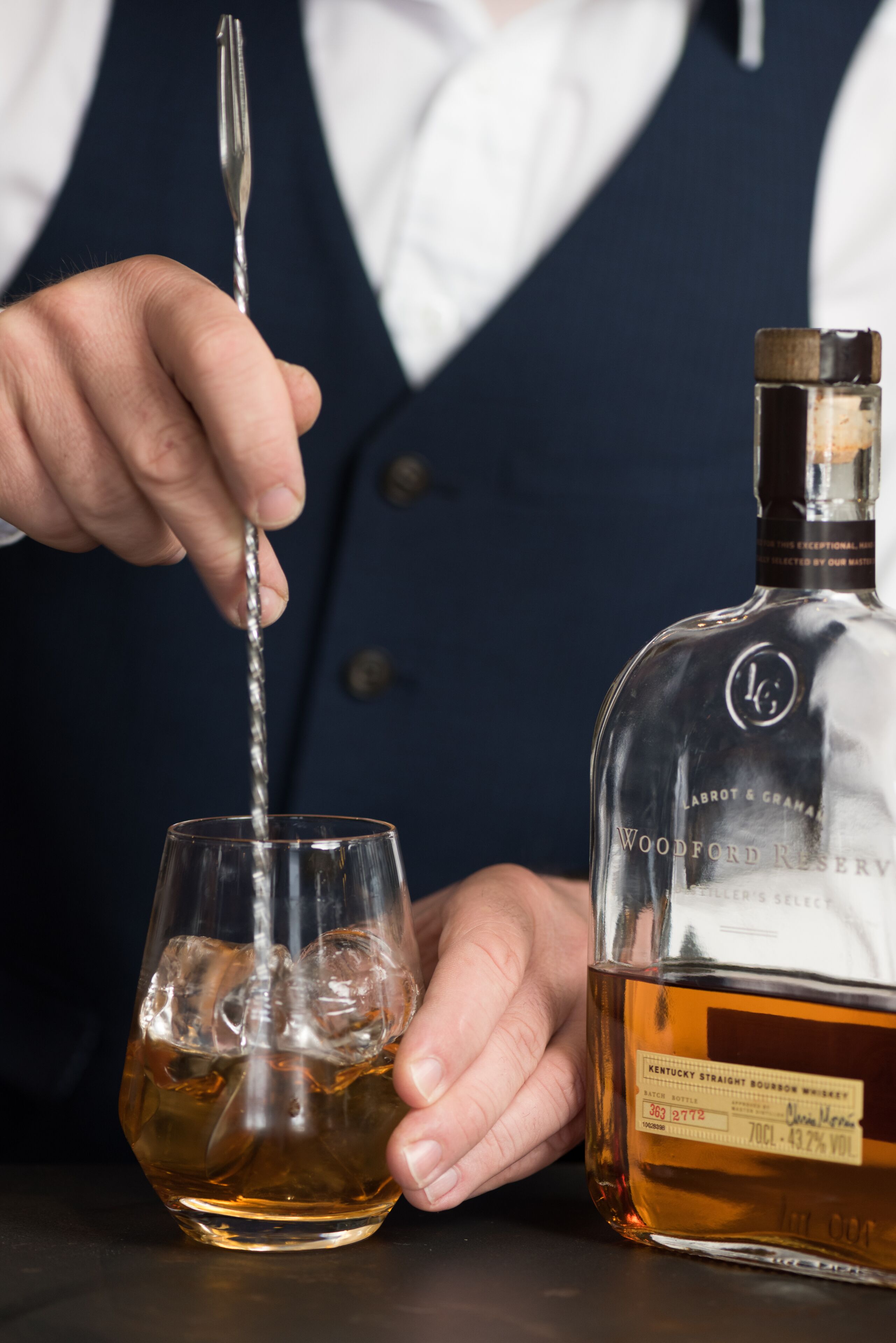 A person pouring whiskey from a bottle into a glass.