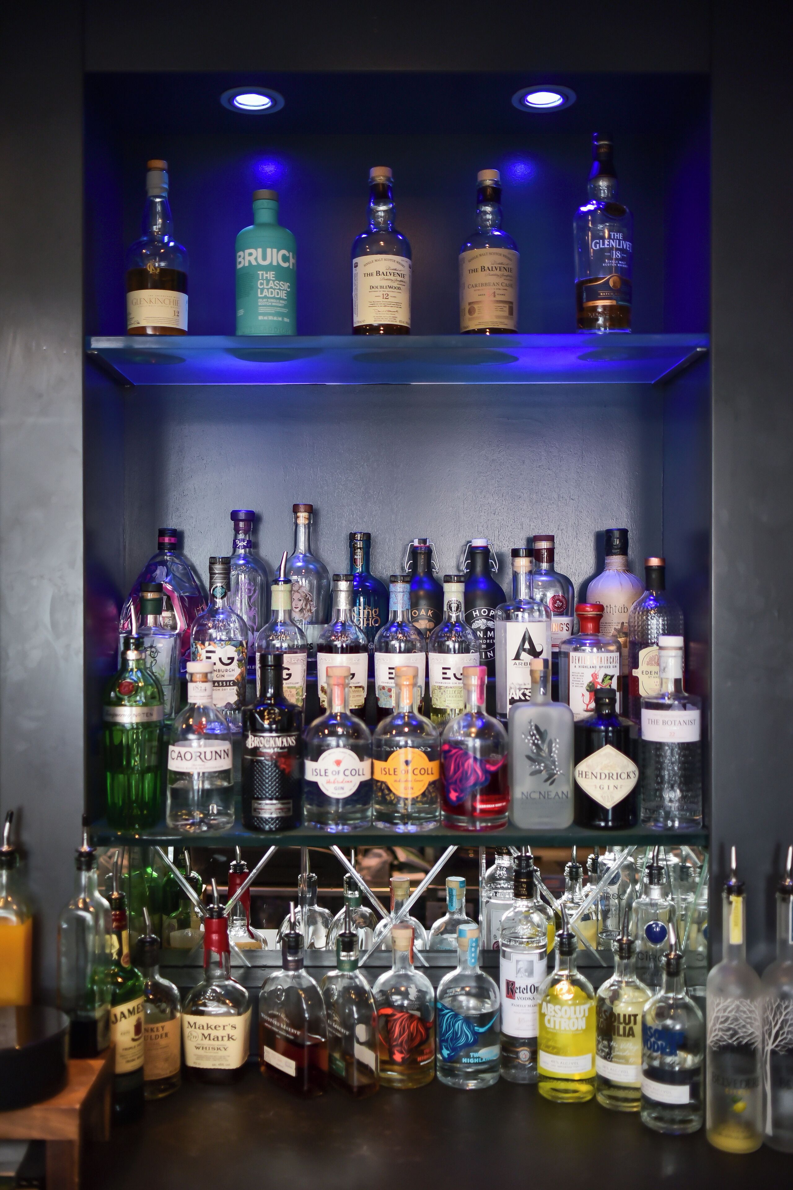 Zona de bar con estantes llenos de botellas de licores.