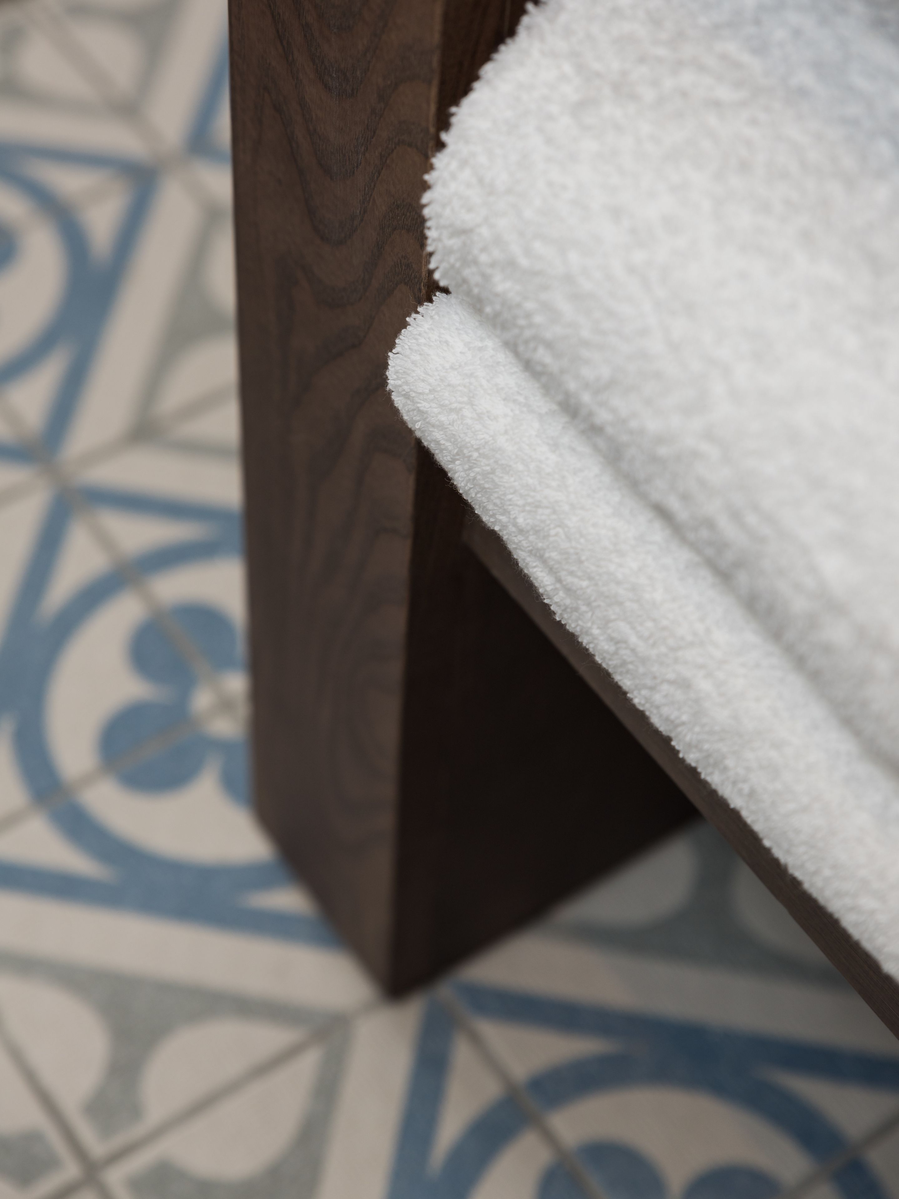 A wooden bench with a white towel draped over it.