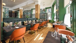 Um restaurante com piso de madeira, paredes verdes e cadeiras laranja.