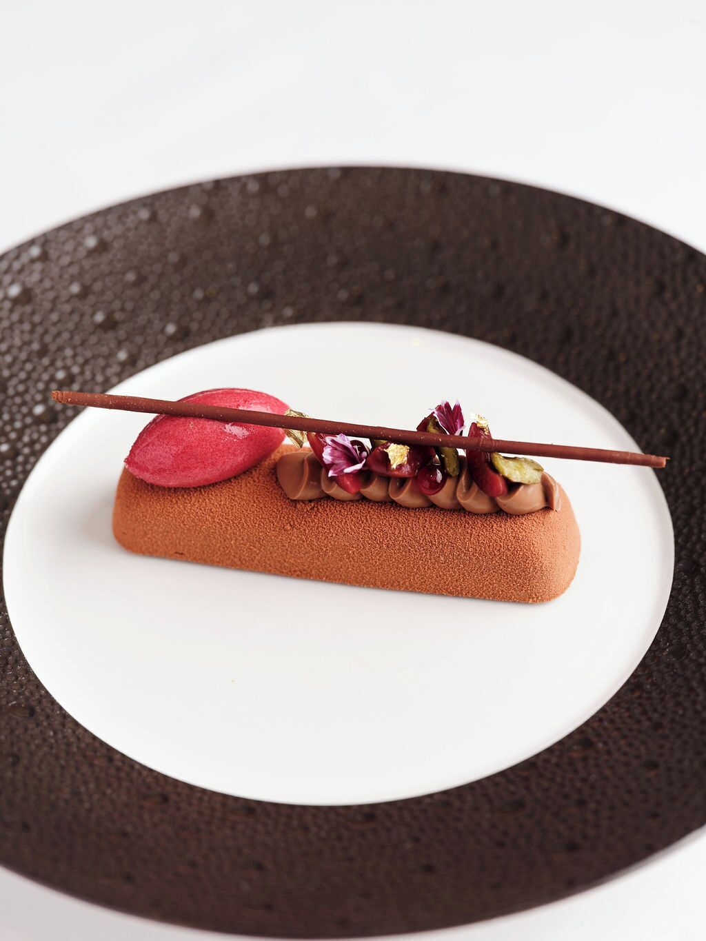 A dessert on a white plate with a dark textured rim.