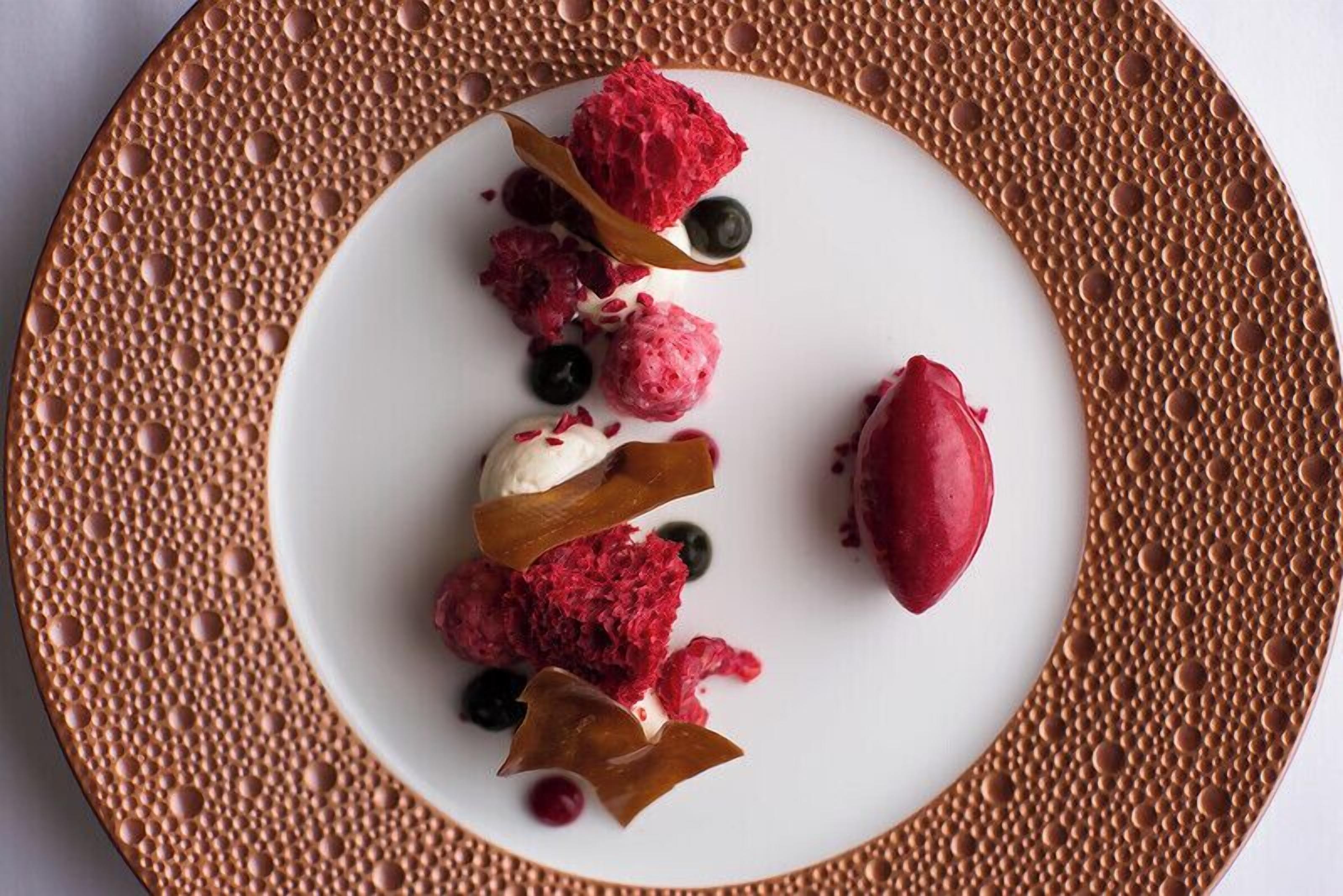 A dessert plate with various berries and a scoop of ice cream.