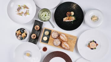 Diversos platos y alimentos dispuestos en fuentes y una tabla de madera, sugiriendo una preparación para comer.