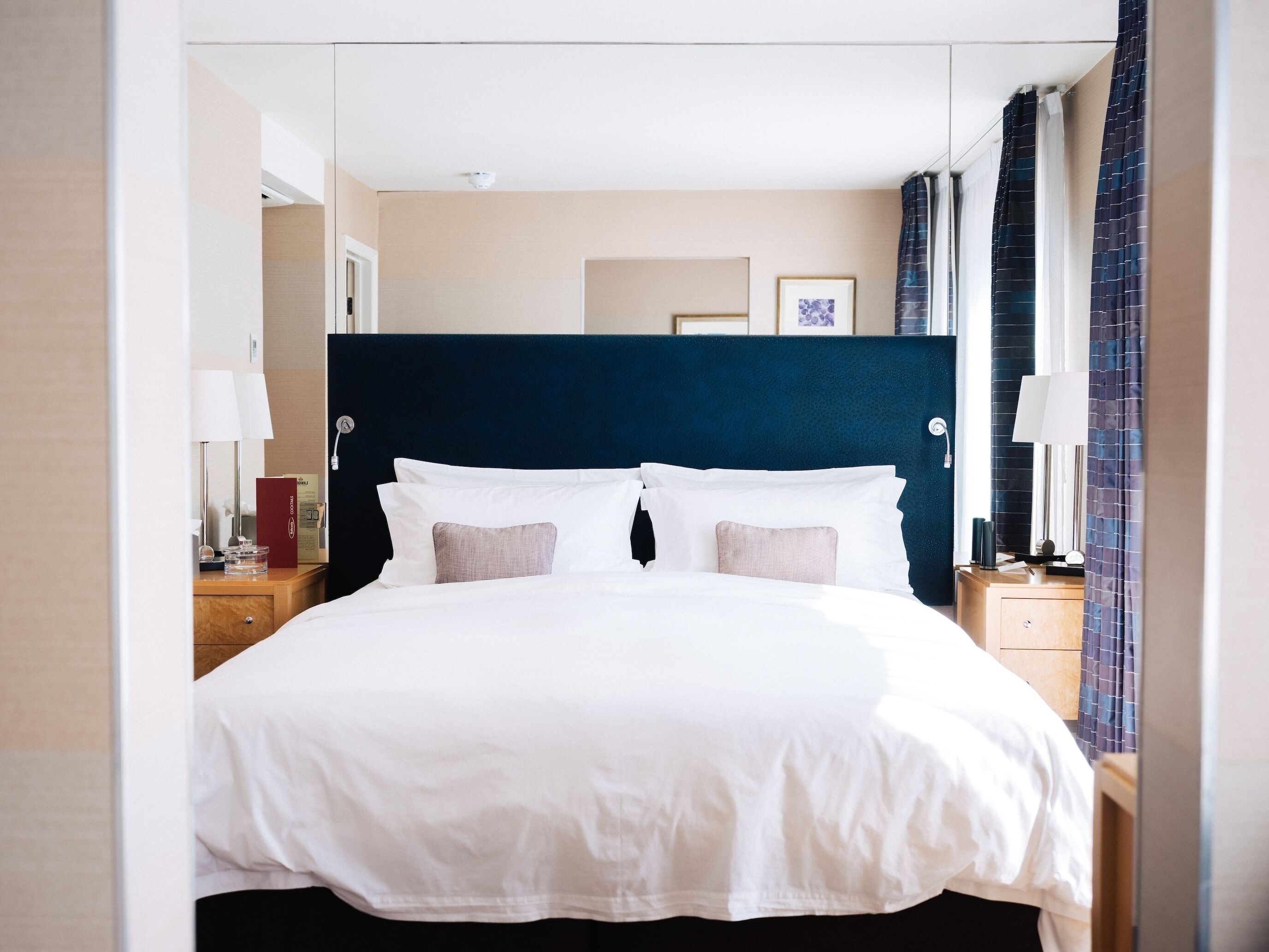 Een moderne hotelkamer met een groot bed, een donker hoofdeinde en uitzicht op de stad door het raam.